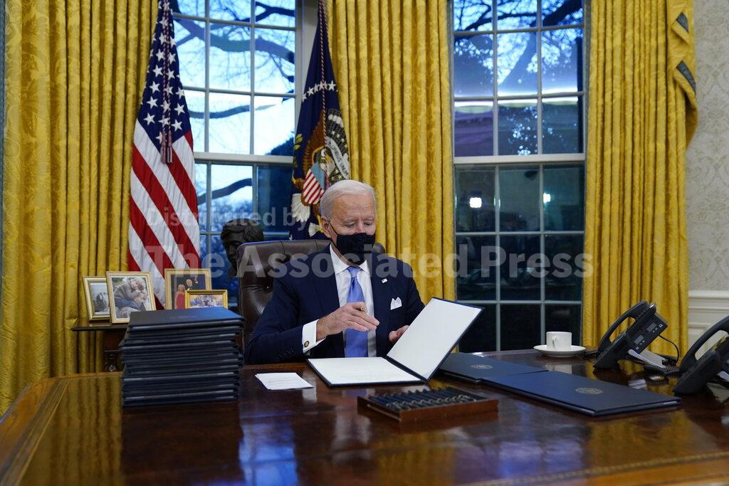 President Joe Biden signs his first executive orders in the Oval Office of the White House on Wednesday, Jan. 20, 2021, in Washington. (AP Photo/Evan Vucci)