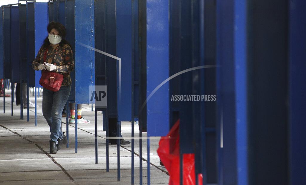 Esteban Felix A woman leaves the voting booth during a referendum to decide whether the country should replace its 40-year-old constitution, in Santiago, Chile, Sunday, Oct. 25, 2020. (AP Photo/Esteban Felix)