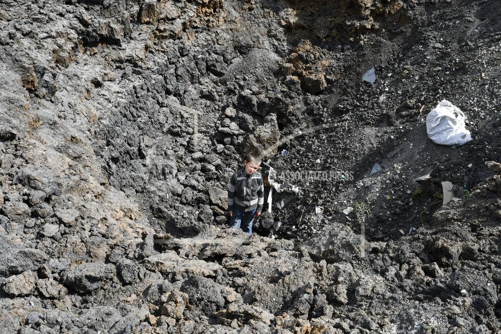 Andriy Andriyenko Maxim stands in the crater of an explosion after Russian shelling next to the Orthodox Skete in honor of St. John of Shanghai in Adamivka, near Slovyansk, Donetsk region, Ukraine, Tuesday, May 10, 2022. (AP Photo/Andriy Andriyenko)