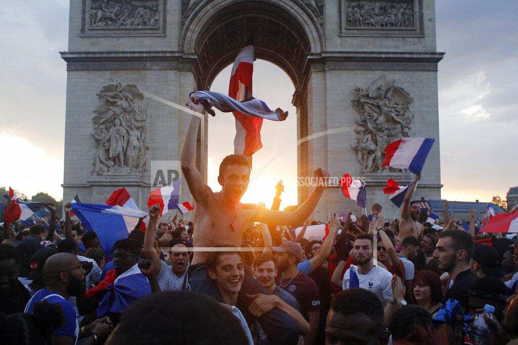 Thibault Camus FILE - In this Sunday, July 15, 2018 file photo, people gather around the Arc de Triomphe in Paris, to celebrate France's World Cup victory over Croatia. On Friday, July 23, 2021, The Associated Press reported on a photo of a blond woman with a flag atop the Arc de Triomphe circulating online, incorrectly asserting it shows recent protests in Paris over the government’s latest coronavirus measures. But the photo shows celebrations in Paris in July 2018 after France won the World Cup, not a recent protest. (AP Photo/Thibault Camus, File)