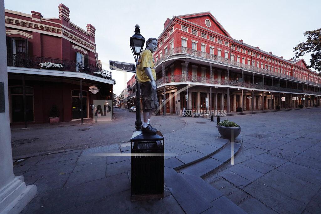 Gerald Herbert FILE - In this March 20, 2020 file photo, street performer Eddie Webb looks around the nearly deserted French Quarter looking to make money in New Orleans. Where political divides marred early recovery efforts after Hurricane Katrina in 2005, Louisiana is showing rare political unity in the fight against the new coronavirus. (AP Photo/Gerald Herbert, File)