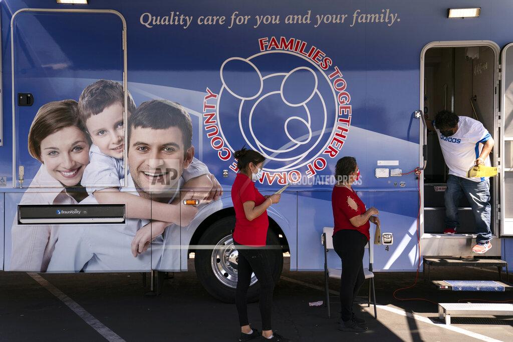 Jae C. Hong Two women wait in line to receive a dose of the Moderna COVID-19 vaccine at a mobile clinic set up in the parking lot of a shopping center in Orange, Calif., Thursday, April 29, 2021. The mobile unit, launched in February by Families Together of Orange County, began its service to provide better access to the COVID-19 vaccine within the community and to prevent vaccine hesitation, according to mobile operations manager Parsia Jahanbani. "There's a lot of people that are hesitant to go to vaccine centers to get vaccinated for various reasons. They might be afraid of not having paperwork. They might be afraid of not being able to take time off from work," said Jahanbani. (AP Photo/Jae C. Hong)