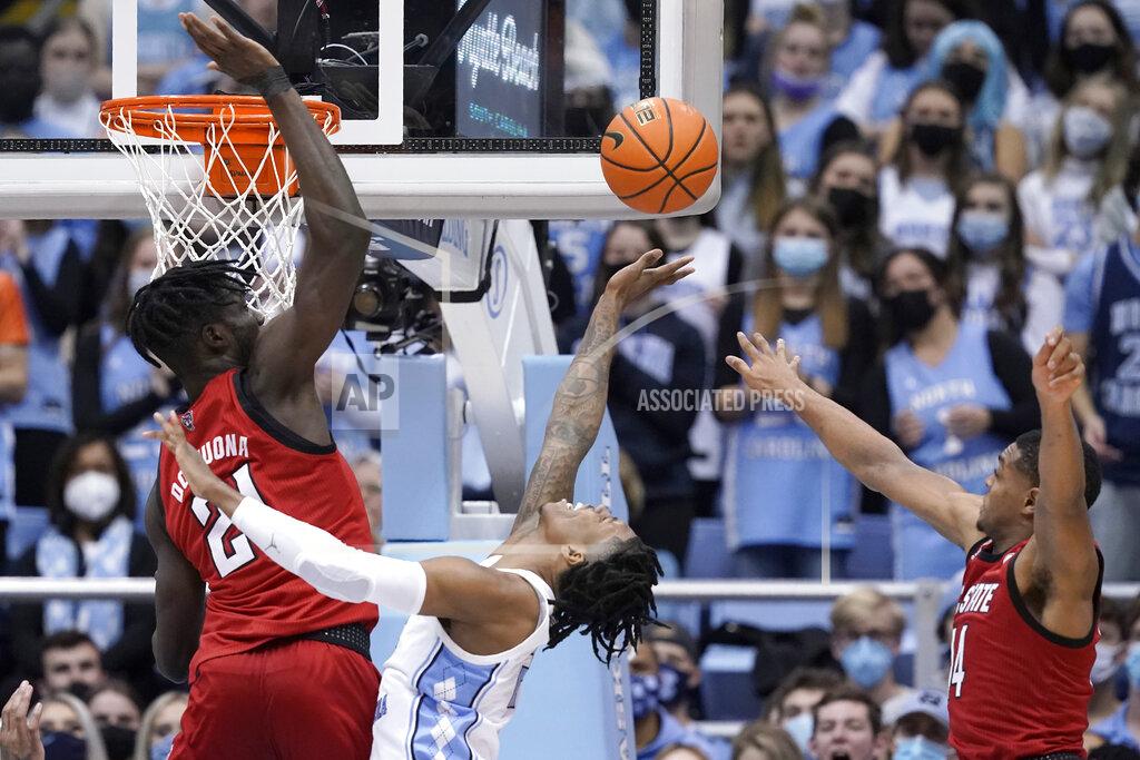 Gerry Broome North Carolina State forward Ebenezer Dowuona (21) and guard Casey Morsell (14) defend against North Carolina guard Caleb Love during the second half of an NCAA college basketball game in Chapel Hill, N.C., Saturday, Jan. 29, 2022. (AP Photo/Gerry Broome)