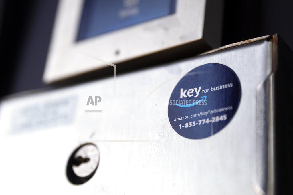 Shafkat Anowar A blue sticker with the Amazon logo is displayed on a buzzer system in the apartment building of Jason Goldberg, chief commerce strategy officer at marketing company Publicis Communications, Monday, March 29, 2021, in Chicago. Amazon is making a push to install a device on buzzer systems in apartment buildings throughout the country that allows its delivery drivers to whip out a phone, tap a button and unlock a building's front doors whenever they need to leave packages in the lobby instead of the street. (AP Photo/Shafkat Anowar)
