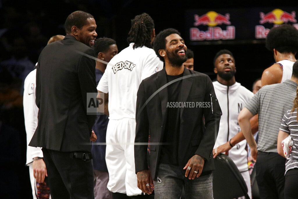 Brooklyn Nets guard Kyrie Irving, center, jokes with forward Kevin Durant, left, during a timeout against the Boston Celtics during the first half of an NBA basketball game Friday, Nov. 29, 2019, in New York. (AP Photo/Adam Hunger)