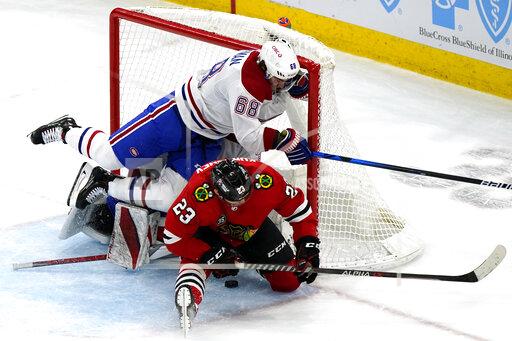 Chicago Blackhawks center Philipp Kurashev (23) scores the game-winning goal against Montreal Canadiens center Mike Hoffman (68) and goaltender Sam Montembeault during overtime period of an NHL hockey game in Chicago, Thursday, Jan. 13, 2022. The Chicago Blackhawks won 3-2 in overtime. (AP Photo/Nam Y. Huh)