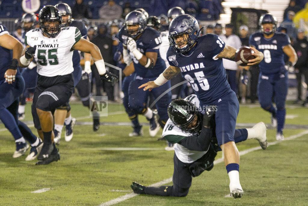 Tom R. Smedes Nevada running back Toa Taua (35) is grabbed by Hawaii's Cortez Davis (18) in the first half of an NCAA college football game in Reno, Nev., Saturday, Sept. 28, 2019. (AP Photo/Tom R. Smedes)