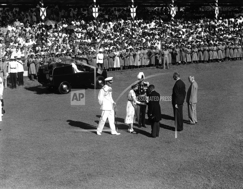 Uncredited FILE - In this file photo dated Nov. 26, 1953, Britain's Queen Elizabeth II shakes hands with E.L. Allen, Minister of Education, at Sabina Park in Kingston, Jamaica, where the Queen and her husband, the Duke of Edinburgh greeted more than 2,000 school children lined up on the park's cricket field. The Duke, left, steps up to greet Mr. Allen as Harold Houghton, second from right, director of Education, and G.M. Dacosta, right, president of the Cricket Club, wait their turns to meet the royal couple. The Queen is the first British ruling monarch in history to visit the British rum and sugar colony. Man wearing plumed hat is not identified. Prince Philip who died Friday April 9, 2021, aged 99, lived through a tumultuous century of war and upheavals, but he helped forge a period of stability for the British monarchy under his wife, Queen Elizabeth II. Philip helped create the Commonwealth of nations, with the queen at its head, in an attempt to bind Britain and its former colonies together on a more equal footing. (AP Photo, FILE)