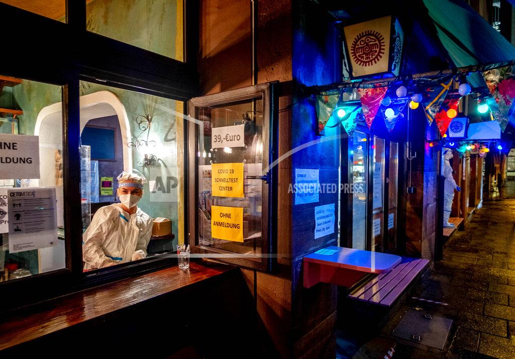 Michael Probst FILE - In this Dec. 15, 2020 file photo, a medical worker waits for customers at a corona quick test center that is located in an empty tequila bar in Frankfurt, Germany. More than 50,000 people have died after contracting COVID-19 in Germany, a number that has risen swiftly over recent weeks as the country has struggled to bring down infection figures. (AP Photo/Michael Probst, File)