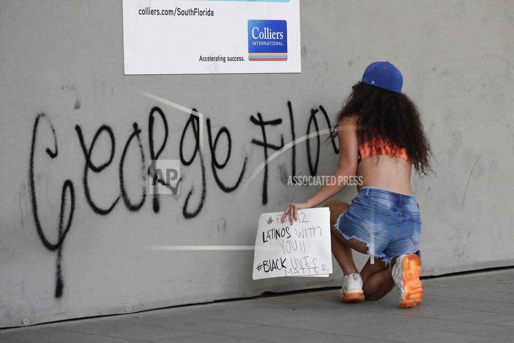 Wilfredo Lee A protester against the death of George Floyd puts graffiti on a wall as she and others demonstrate Sunday, May 31, 2020, in Miami. Floyd died after being restrained by Minneapolis police officers on May 25. (AP Photo/Wilfredo Lee)