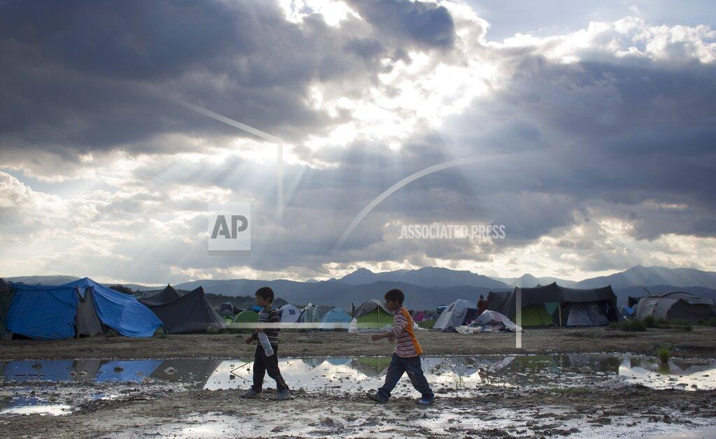 Darko Bandic FILE - In this Sunday, May 22, 2016 file photo, two boys walk past ground water at the migrant camp in Idomeni, northern Greece. Five years on, the deal between European Union and Turkey is no longer working but at a summit next week EU leaders will discuss ways to improve relations with Turkey and could try to revive the agreement. (AP Photo/Darko Bandic, File)