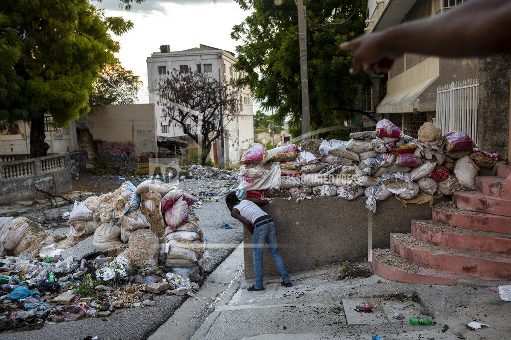 Rodrigo Abd A lookout keeps an eye on rival gangsters in downtown Port-au-Prince, Haiti, Tuesday, Sept. 14, 2021. One of the most powerful groups is the G9 coalition of gangs led by Jimmy Cherizier, alias "Barbecue," a former policeman turned gangster. His gang coalition controls the empty streets around the judiciary and legislative buildings, and all streets east to the coast. (AP Photo/Rodrigo Abd)