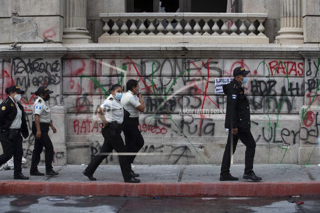 Moises Castillo Police officers patrol in front of the Congress building that was damaged during protests in Guatemala City, Sunday, Nov. 22, 2020. Protesters broke into the building and set it partially on fire amid growing demonstrations against President Alejandro Giammattei and the legislature for approving a controversial budget that cut educational and health spending. (AP Photo/Moises Castillo)