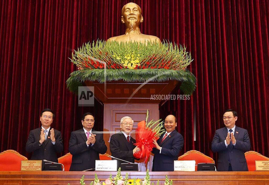 Lê Trí Dũng Vietnam Communist party General Secretary Nguyen Phu Trong, center left, is presented with a bouquet by Prime Minister Nguyen Xuan Phuc, center right, in Hanoi, Vietnam, Sunday, Jan. 31, 2021. Vietnam Communist Party has re-elected Nguyen Phu Trong for another term as the party's General Secretary, the country de-facto top leader. Other officials from left; Vo Van Thuong, Secretary of the Central Committee, Pham Minh Chinh, head of the Central Organization Committee and Vuong Dinh Hue, Hanoi Secretary of the Communist Party (Le Tri Dung/VNA via AP)