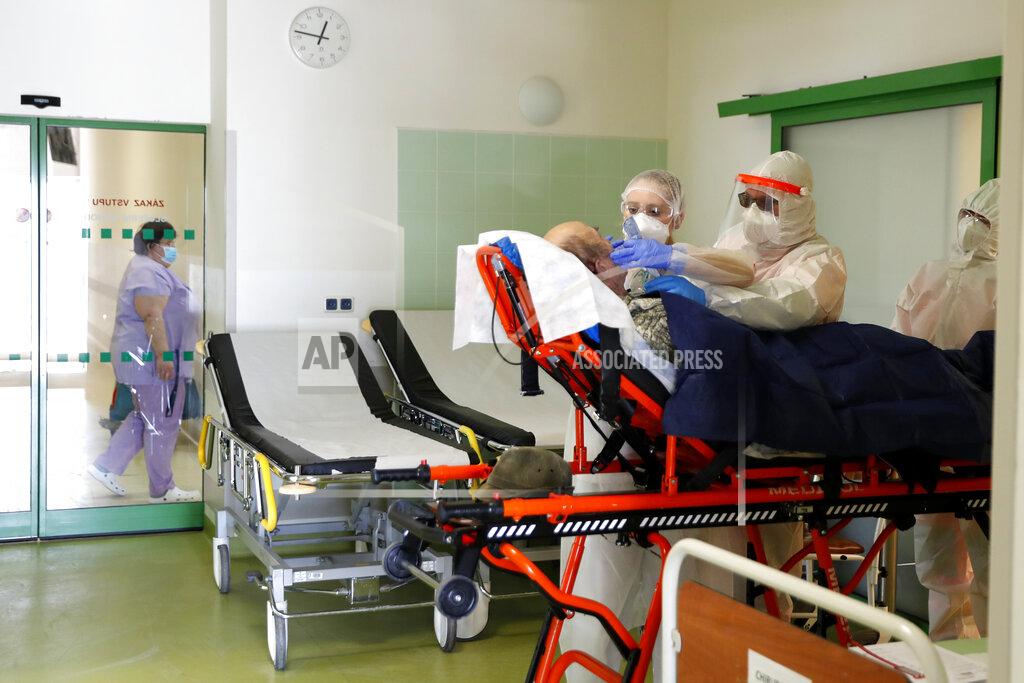 FILE - In this Friday, Feb. 12, 2021, file photo, medical workers move a covid-19 patient at a hospital overrun by the covid pandemic in Cheb, Czech Republic. The Czech government has decided to further tighten restrictive measures amid a surge of a highly contagious coronavirus variant in one of the hardest-hit European Union's nations. At the same time, the worsening situation has forced the Cabinet to abandon for now its plans to reopen all stores as soon as next week. (AP Photo/Petr David Josek/File)