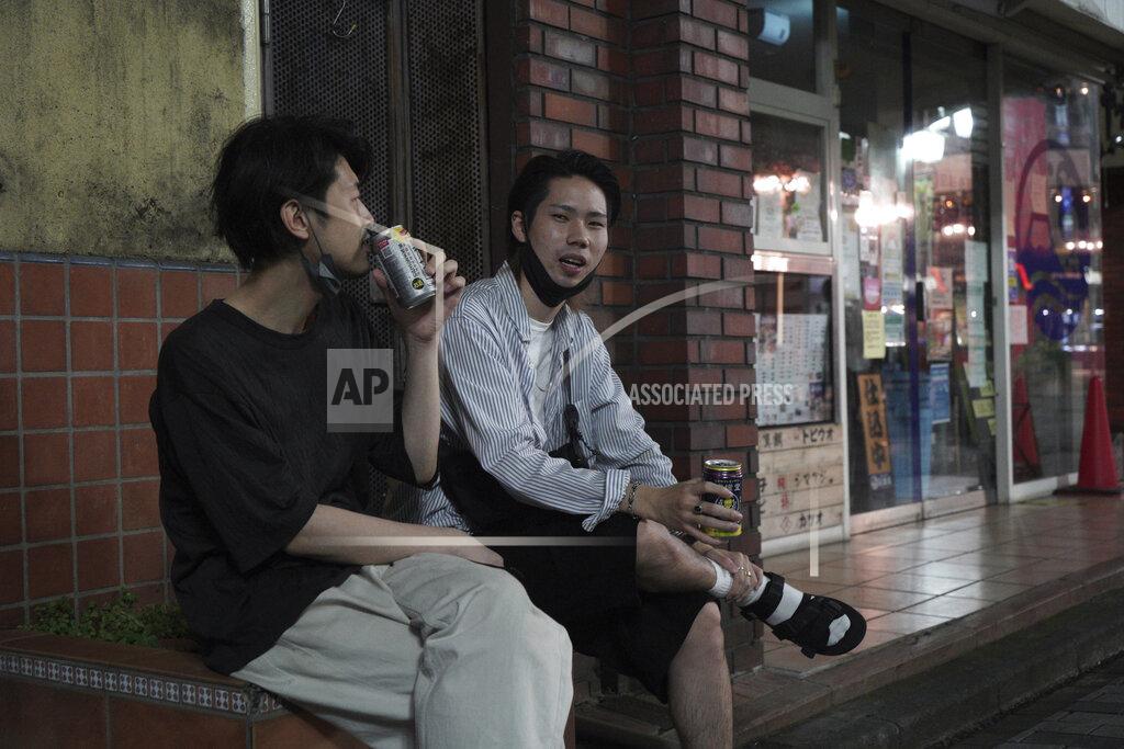 Kantaro Komiya Naoto Suga, right, 25, drinks canned alcohol roadside with his friend in Tokyo’s Shinjuku district Monday, July 19, 2021. "I don’t think the Olympics itself made this (situation), but even before the Games, things like the state of emergency have remained half measures, and I think that's making things worse," Suga said. "People are all used to the state of emergency, so it's getting less meaningful now." (AP Photo/Kantaro Komiya)