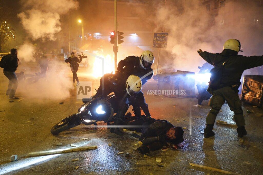 Aggelos Barai A policeman lays injured on the road after an attack by protesters as his colleagues try to help him during clashes in Athens, Tuesday, March 9, 2021. Severe clashes broke out Tuesday in Athens after youths protesting an incident of police violence attacked a police station with petrol bombs, and severely injured one officer. (AP Photo/Aggelos Barai)