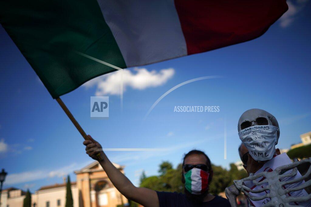 Andrew Medichini A man waves an Italian flag during a protest against the government restriction measures to curb the spread of COVID-19, in Rome, Saturday, Oct. 10, 2020. (AP Photo/Andrew Medichini)