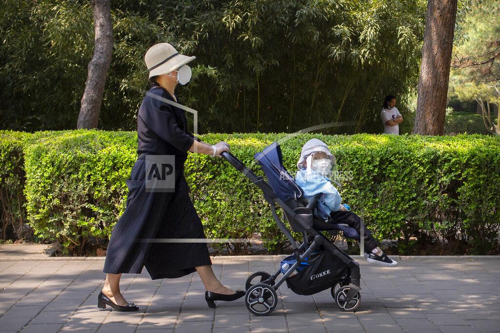 Mark Schiefelbein A woman and a child wear face masks to protect against the new coronavirus as they walk through a public park in Beijing, Saturday, May 2, 2020. China, where the pandemic began in December, reported one new infection and no deaths in the 24 hours through midnight Friday. (AP Photo/Mark Schiefelbein)