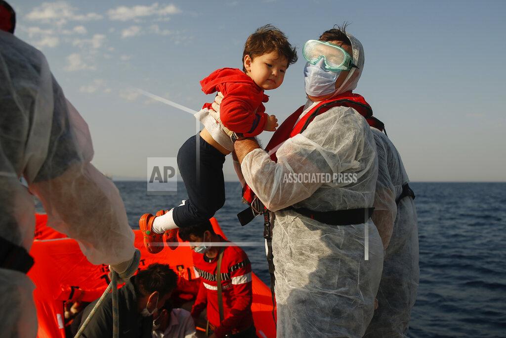 Emrah Gurel A Turkish coast guard officer, wearing protective gear to help prevent the spread of coronavirus, carries a child off a life raft during a rescue operation in the Aegean Sea, between Turkey and Greece, Saturday, Sept. 12, 2020. Turkey is accusing Greece of large-scale pushbacks at sea — summary deportations without access to asylum procedures, in violation of international law. The Turkish coast guard says it rescued over 300 migrants "pushed back by Greek elements to Turkish waters" this month alone. Greece denies the allegations and accuses Ankara of weaponizing migrants. (AP Photo/Emrah Gurel)