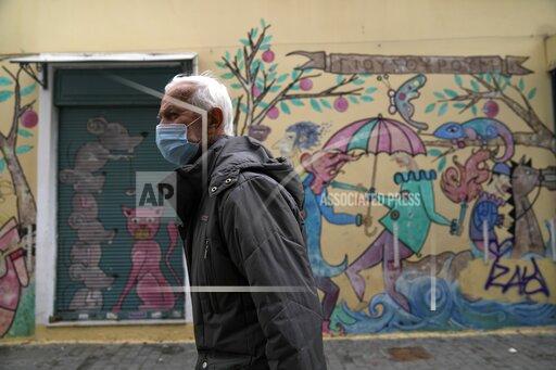 A man wearing a face mask to protect against coronavirus walks in Athens, Greece, Monday, Nov. 29, 2021. Greece has recorded a spike in deaths and infections related to COVID-19 this month, amid heightened concerns in Europe due to the Omicron variant. The Greek government has ruling out the prospect of a general lockdown. (AP Photo/Thanassis Stavrakis)