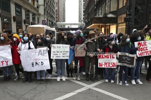 Protesters calling for better COVID-19 health and safety procedures in Chicago public schools briefly block traffic at State Street and Madison Street in Chicago near Chicago Public Schools headquarters on Friday, Jan. 14, 2022. (Terrence Antonio James/Chicago Tribune via AP)