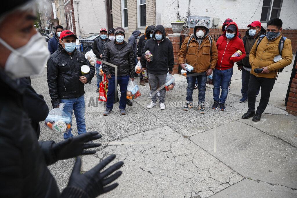 John Minchillo Fabian Arias, left, a Lutheran pastor with Saint Peter's Church in Manhattan, speaks to men who gathered to receive his food donations on a sidewalk, about the importance of social distancing, Friday, May 8, 2020, in the Brooklyn borough of New York. (AP Photo/John Minchillo)