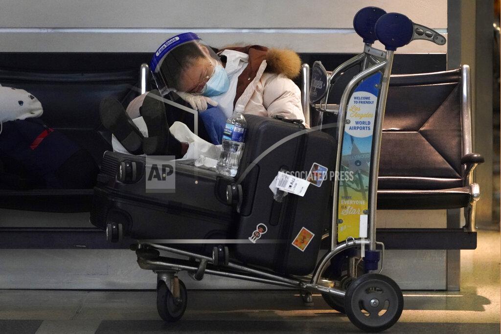 Marcio Jose Sanchez FILE - A traveler sleeps while waiting at a terminal at the Los Angeles International Airport Wednesday, Dec. 23, 2020, in Los Angeles. Among the slow trickle of information coming out of China in advance of next February’s Olympics was news that, with only a handful of flights operating between the U.S. and China, American Olympians will most likely reach Beijing through a still-undetermined set of connecting flights that could more than double their travel time.(AP Photo/Marcio Jose Sanchez, File)