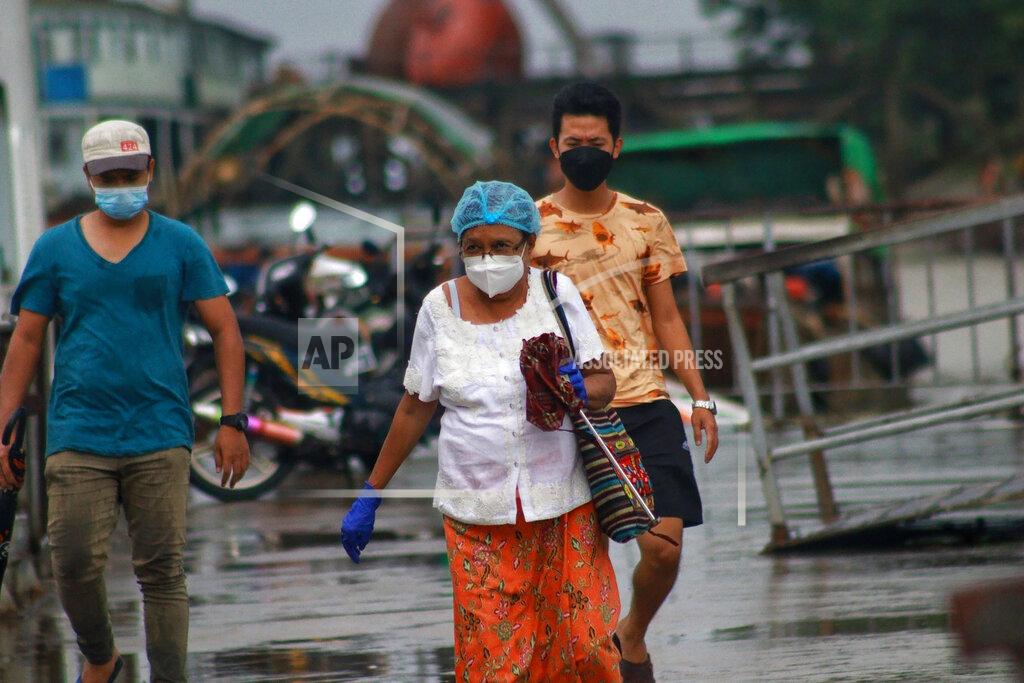Uncredited People wear face masks as they walk outside the Dala jetty in Yangon, Myanmar Tuesday, July 27, 2021. (AP Photo)