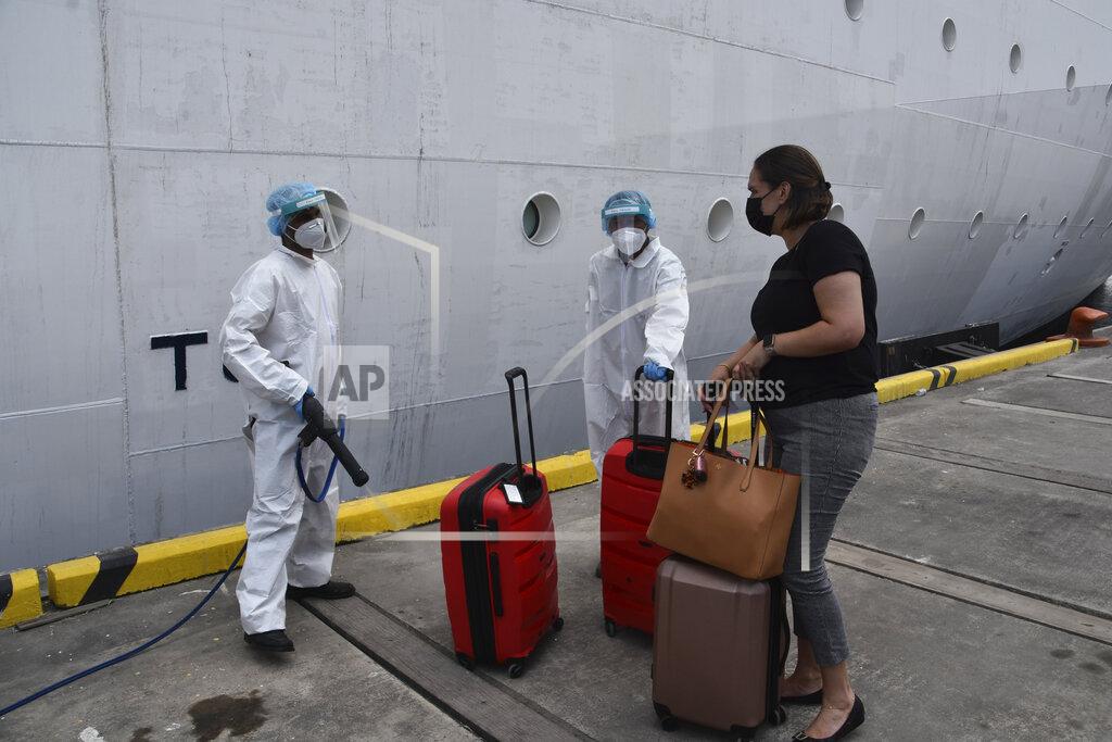 Orvil Samuel A healthcare worker disinfects the luggage of an evacuee before boarding the Royal Caribbean cruise ship Reflection, in Kingstown, on the eastern Caribbean island of St. Vincent, Friday, April 16, 2021. La Soufriere volcano has shot out another explosive burst of gas and ash Friday morning as the cruise ship arrived to evacuate some of the foreigners who had been stuck on a St. Vincent island by a week of violent eruptions. (AP Photo/Orvil Samuel)