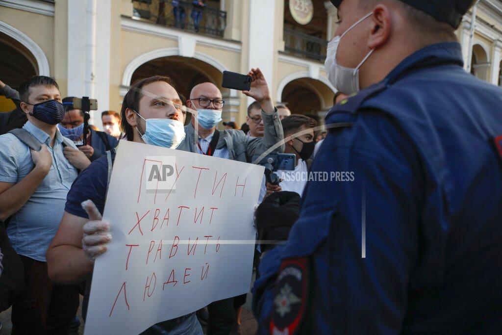 Elena Ignatyeva A protester stands in front of a police officer holding a poster reading "Putin stop poisoning people!" during a picket in support of Russian opposition leader Alexei Navalny in the center of St. Petersburg, Russia, Thursday, Aug. 20, 2020. Russian opposition politician Alexei Navalny is on a hospital ventilator in a coma, after falling ill from a suspected poisoning, according to his spokeswoman Kira Yarmysh. (AP Photo/Elena Ignatyeva)