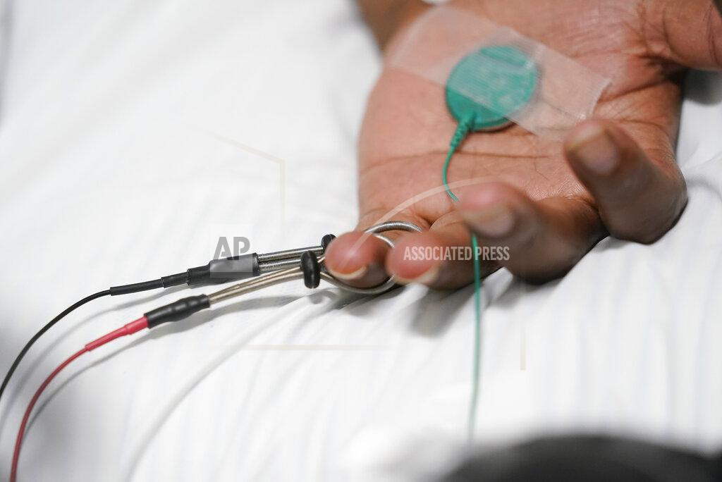 Darron Cummings Larry Brown has his hand tested by Dr. Jerry Smartt, Monday, Aug. 17, 2020, in Carmel, Ind. The doctor attached electrodes to Brown's arms and sent mild pulses of electricity through them to gauge how well his nerves were responding. (AP Photo/Darron Cummings)