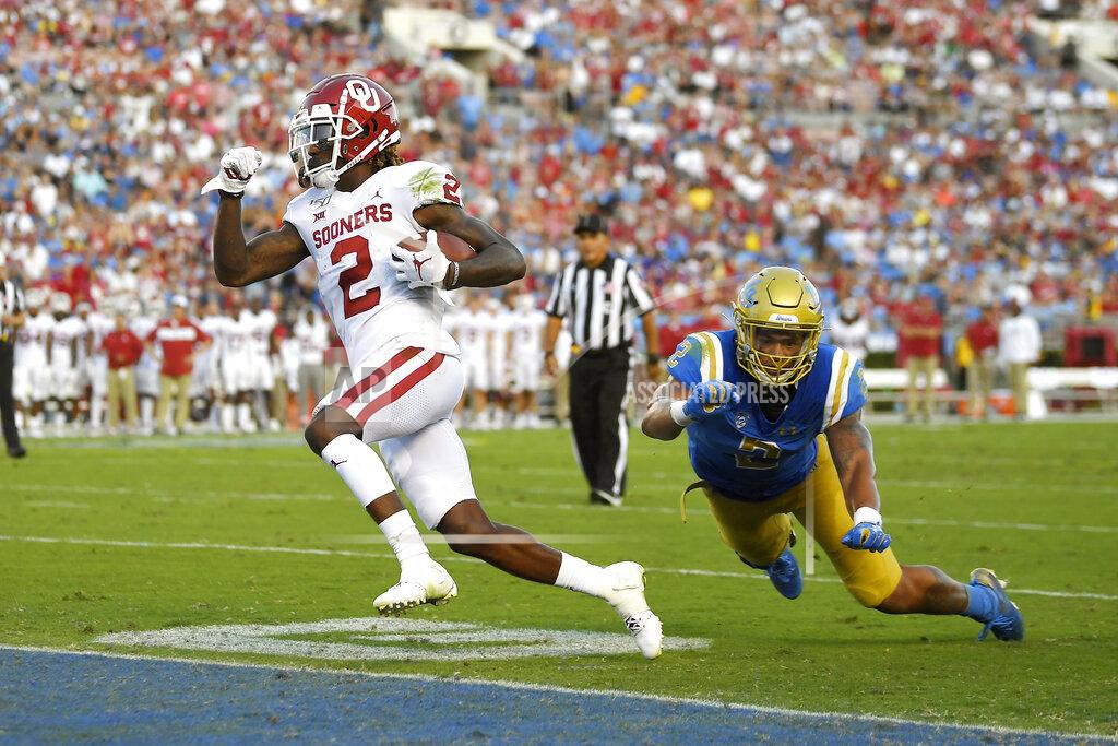 Mark J. Terrill Oklahoma wide receiver CeeDee Lamb, left, runs in for a touchdown as UCLA linebacker Josh Woods defends during the first half of an NCAA college football game Saturday, Sept. 14, 2019, in Pasadena, Calif. (AP Photo/Mark J. Terrill)