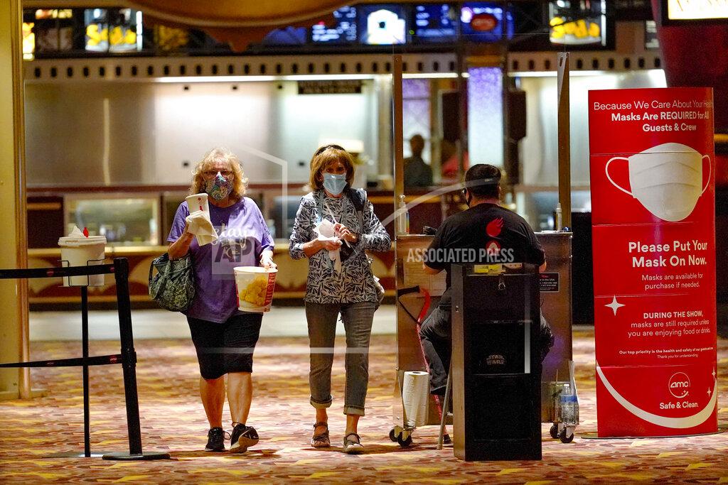 Keith Srakocic Betty Gallagher, left, carries popcorn and drinks beside Mary MacBeth as they pass by the ticket checkpoint, heading off to see, "I Still Believe", one of the first showings at the AMC theatre when it re-opened for the first time since shutting down at the start of the COVID-19 pandemic, Thursday, Aug. 20, 2020, in West Homestead, Pa. (AP Photo/Keith Srakocic)