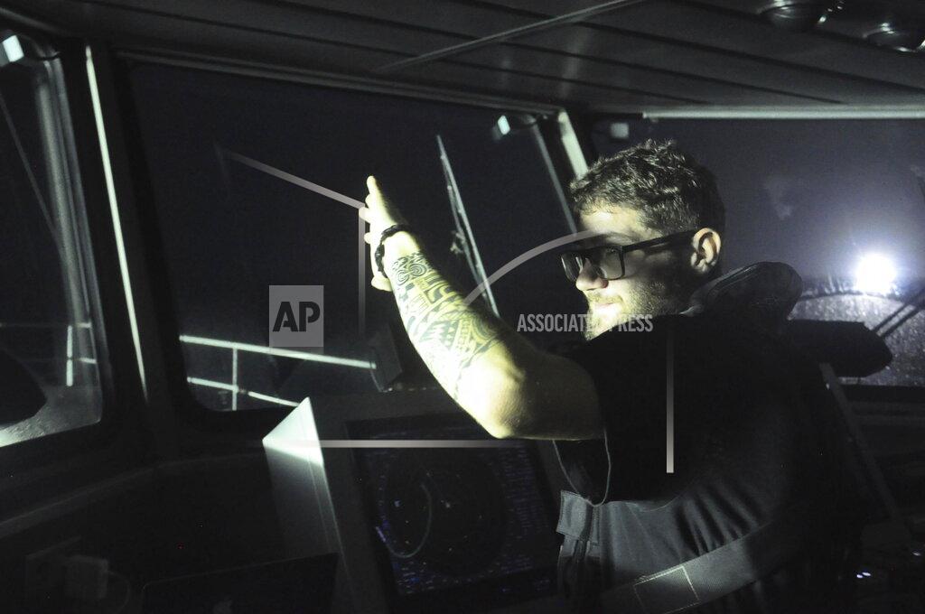 Joshua Goodman Filippo Marini, the third officer aboard the Ocean Warrior, shields his eyes from the light of several Chinese-flagged vessels fishing for squid at night on the high seas off the west coast of South America on July 19, 2021. Marini is an activist for Sea Shepherd, a Netherlands-based oceans conservation group. (AP Photo/Joshua Goodman)