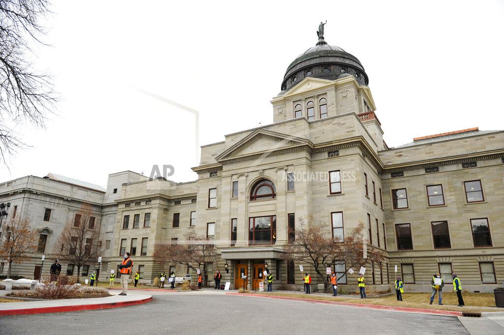 FILE - This Jan. 4, 2021 file photo shows the Montana State Capitol as demonstrators urge people to wear masks in Helena, Mont. The Montana House Judiciary Committee voted Tuesday, Feb. 23, 2021, to advance a bill that would ban discrimination based on vaccination status and prohibit the use of vaccination status to grant or deny services or access to businesses. (Thom Bridge/Independent Record via AP, File)