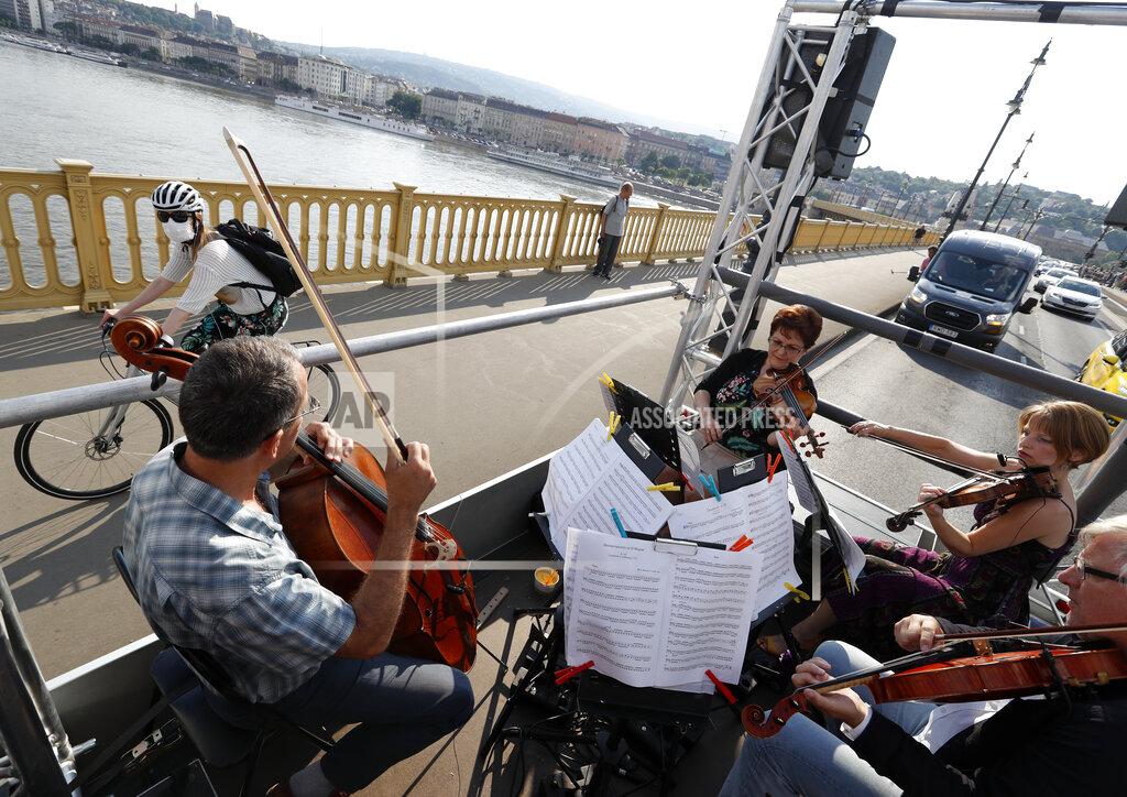 Laszlo Balogh Members of the Budapest Festival Orchestra play music on the back of a truck while driving through downtown Budapest, Hungary, Wednesday June 9, 2021. The prestigious orchestra, founded and led by renowned composer Ivan Fischer, took to the streets as five members of the orchestra performed classical music to motorists and passers-by. The musical parade was aimed at encouraging Hungarians to start returning to live performances in concert halls as the pandemic wanes, after more than a year in which people were homebound and forced to take in their culture online. (AP Photo/Laszlo Balogh)