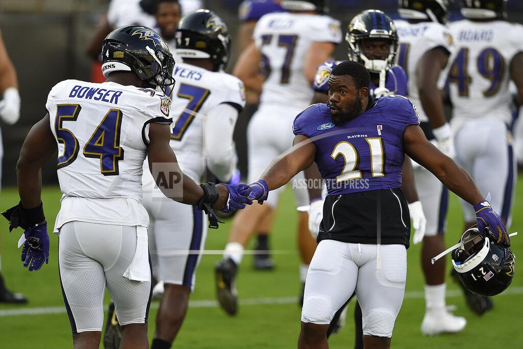 Gail Burton FILE - Baltimore Ravens Mark Ingram II, right, shakes hands with Tyrus Bowser during an NFL football training camp practice, Saturday, Aug. 29, 2020, in Baltimore, Md. They'll be playing Sunday in an empty stadium, facing a Cleveland Browns team with a new coaching staff that’s provided no clue how they plan to employ a revamped offense. (AP Photo/Gail Burton, FILE)