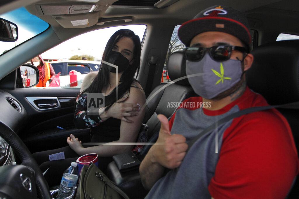 Cedar Attanasio Jennifer Ungefug, 29, holds her arm after getting a dose of the Moderna COVID-19 vaccine as fiance Darrell McDonald, 33, give a thumbs up on Friday, April 23, 2021, in Santa Fe, N.M. McDonald said he'd gotten a dose a few days before. New Mexico education and health officials are organizing vaccine drives targeting students ahead of summer break. Children aged 16 and 17 can only get the Pfizer vaccine, for now. (AP Photo/Cedar Attanasio)