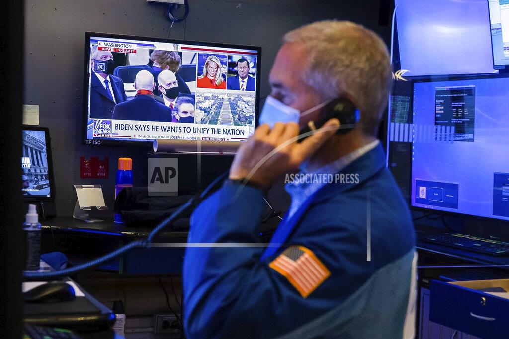 Colin Ziemer In this photo provided by the New York Stock Exchange, the presidential inaugural plays on a screen as trader Timothy Nick works in a booth on the trading floor, Wednesday, Jan. 20, 2021. U.S. stocks are rallying to records Wednesday on encouraging earnings reports and continued optimism that new leadership in Washington will mean more support for the struggling economy. (Colin Ziemer/New York Stock Exchange via AP)