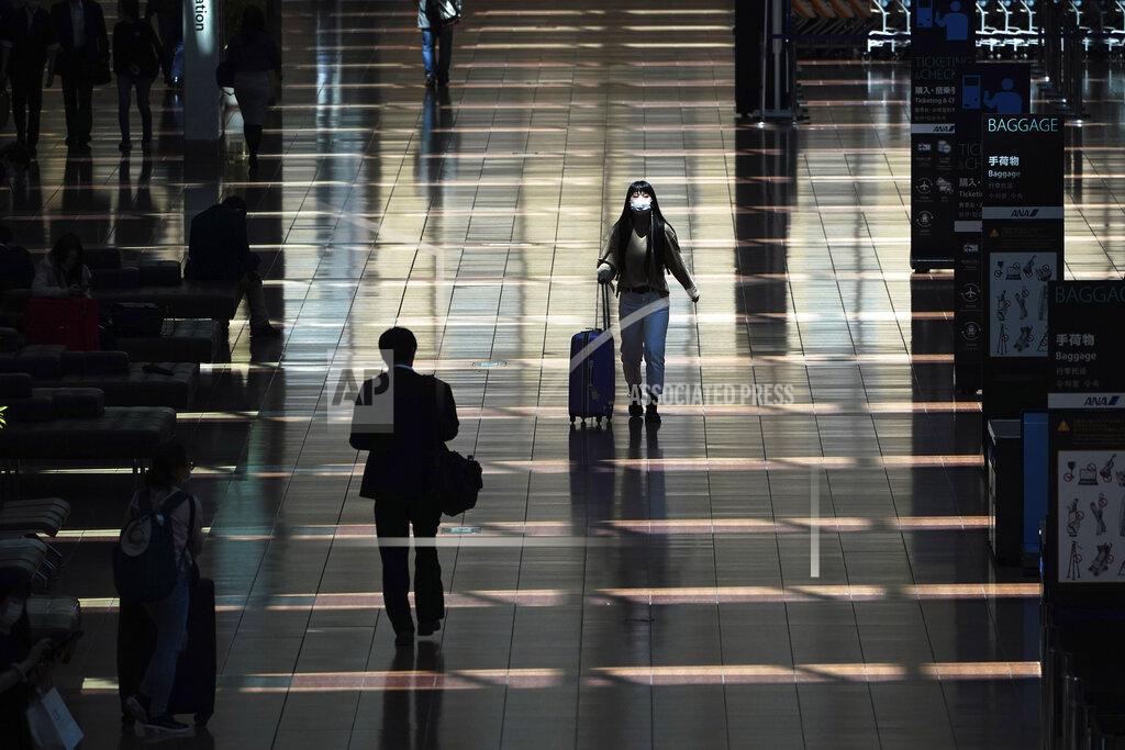 Eugene Hoshiko FILE - In this April 29, 2020, file photo, a few passengers walk at a domestic terminal of Haneda Airport in Tokyo, at the start of "Golden Week" holidays. Under Japan's coronavirus state of emergency, people have been asked to stay home. Many are not. Some still have to commute to their jobs despite risks of infection, while others are dining out, picnicking in parks and crowding into grocery stores with scant regard for social distancing. (AP Photo/Eugene Hoshiko, File)