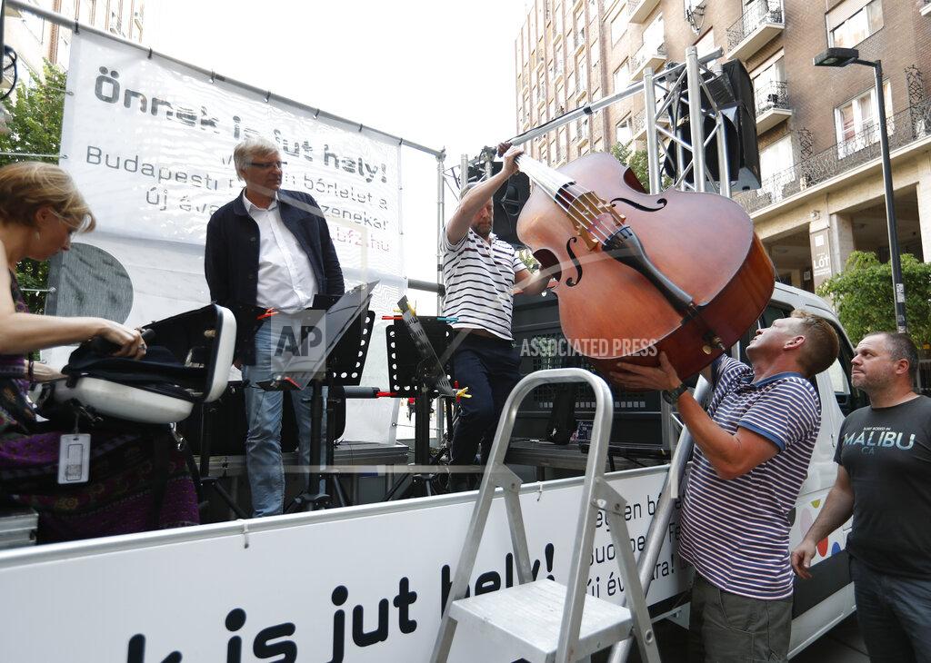 Laszlo Balogh Members of the Budapest Festival Orchestra play music on the back of a truck while driving through downtown Budapest, Hungary, Wednesday June 9, 2021. The prestigious orchestra, founded and led by renowned composer Ivan Fischer, took to the streets as five members of the orchestra performed classical music to motorists and passers-by. The musical parade was aimed at encouraging Hungarians to start returning to live performances in concert halls as the pandemic wanes, after more than a year in which people were homebound and forced to take in their culture online. (AP Photo/Laszlo Balogh)
