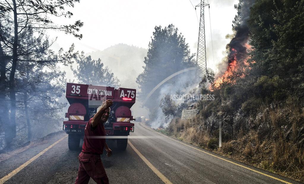 Ismail Coskun Firefighters work as the wildfires engulf an area near the seashore, forcing people to be evacuated by boats, in Bodrum, Mugla, Turkey, Sunday, Aug. 1, 2021. Wildfires in the Turkish holiday destinations of Antalya and Mugla are still raging as firefighters worked to battle the blazes for a fifth day. Authorities warned tourists and residents to keep evacuating Turunc, a town in the seaside resort of Marmaris, and navy ships waited in the sea there to see if a bigger evacuation was needed. (Ismail Coskun/IHA via AP)