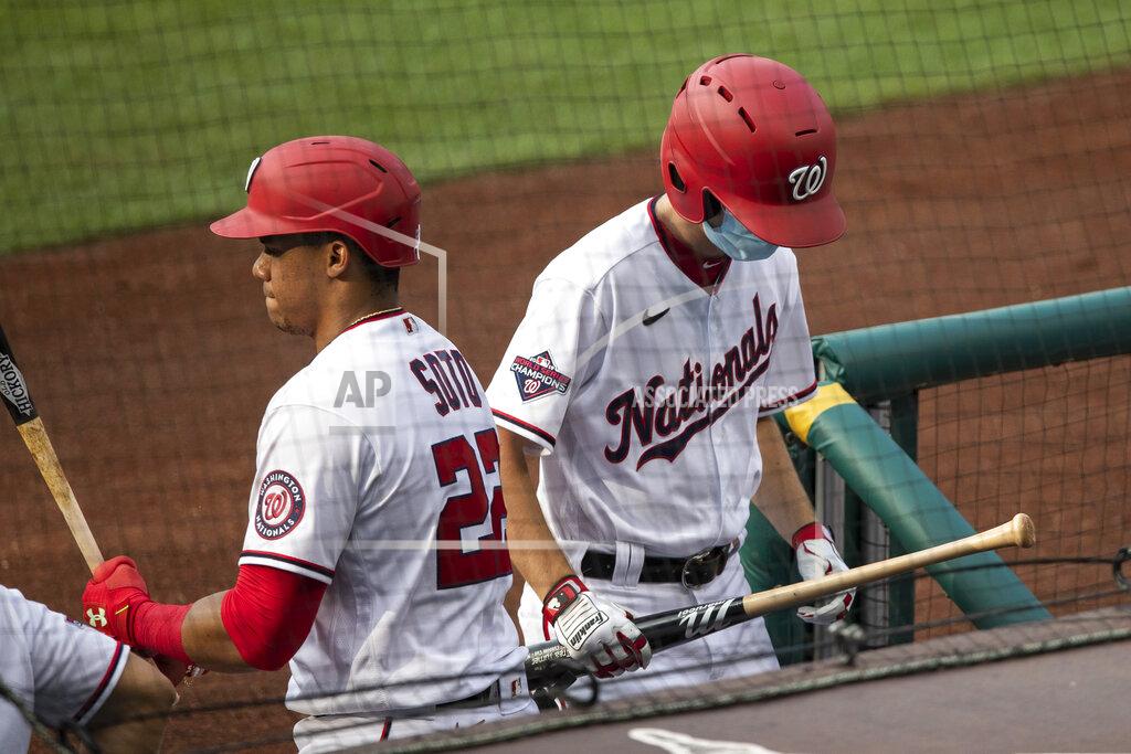 Alex Brandon A bat boy walks into the dugout with a bat, past Washington Nationals' Juan Soto (22) during the first inning of an exhibition baseball game against the Baltimore Orioles at Nationals Park, Tuesday, July 21, 2020, in Washington. (AP Photo/Alex Brandon)