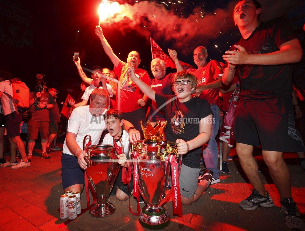 Jon Super Liverpool supporters with replica Premier League and Champions League trophies as they celebrate outside of Anfield Stadium in Liverpool, England, Thursday, June 25, 2020 after Liverpool clinched the English Premier League title. Liverpool took the title after Manchester City failed to beat Chelsea on Wednesday evening. (AP photo/Jon Super)