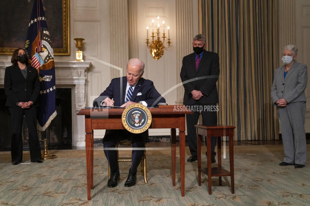 Evan Vucci President Joe Biden signs a series of executive orders on climate change, in the State Dining Room of the White House, Wednesday, Jan. 27, 2021, in Washington. From left, Vice President Kamala Harris, Biden, White House science adviser Dr. Eric Lander, and National Climate Adviser Gina McCarthy. (AP Photo/Evan Vucci)