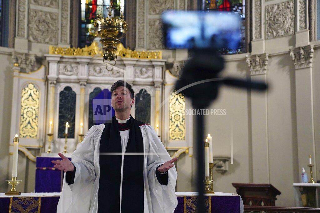 FILE - In this March 29, 2020 file photo, the Rev. Steven Paulikas, rector at All Saints Episcopal Church, delivers an evening prayer service over Facebook Live in the Brooklyn borough of New York. Even amid a mass coronavirus vaccine distribution effort, religious communities will continue to wrestle with the pandemic’s impact on in-person worship. (AP Photo/Emily Leshner)