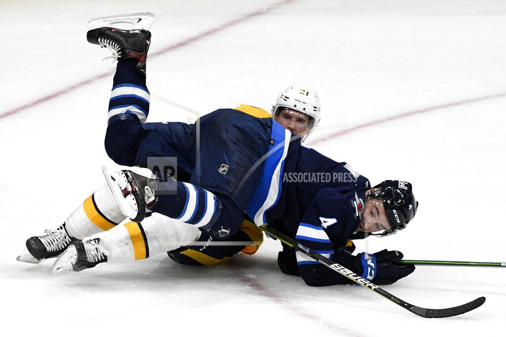 Fred Greenslade Winnipeg Jets' Neal Pionk (4) falls on Nashville Predators' Nick Cousins (21) during the second period of NHL hockey game action in Winnipeg, Manitoba, Saturday, Oct. 23, 2021. (Fred Greenslade/The Canadian Press via AP)