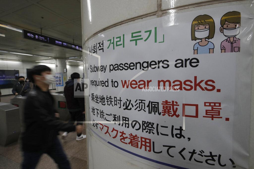 Lee Jin-Man People wearing face masks as a precaution against the coronavirus, walk past a banner at a subway station in Seoul, South Korea, Friday, Nov. 13, 2020. South Korea has reported its biggest daily jump in COVID-19 cases in 70 days as the government began fining people who fail to wear masks in public. From Friday, officials started to impose fines of up to 100,000 won ($90) for people who fail to properly wear masks in public transport and a wide range of venues, including hospitals, nursing homes, pharmacies, nightclubs, karaoke bars, religious and sports facilities and at gatherings of more than 500 people. (AP Photo/Lee Jin-man)