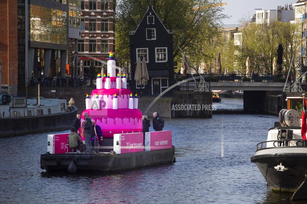 Peter Dejong A huge inflatable pink cake with candles spouting rainbow flames glided through the Amsterdam canals Thursday as the Dutch capital celebrated the 20th anniversary of the world's first legal same-sex marriages, Thursday, April 1, 2021. Twenty years ago, the mayor of Amsterdam married four couples in City Hall as the Netherlands became the first country in the world with legalized same-sex marriage. It's now legal in 28 countries. (AP Photo/Peter Dejong)
